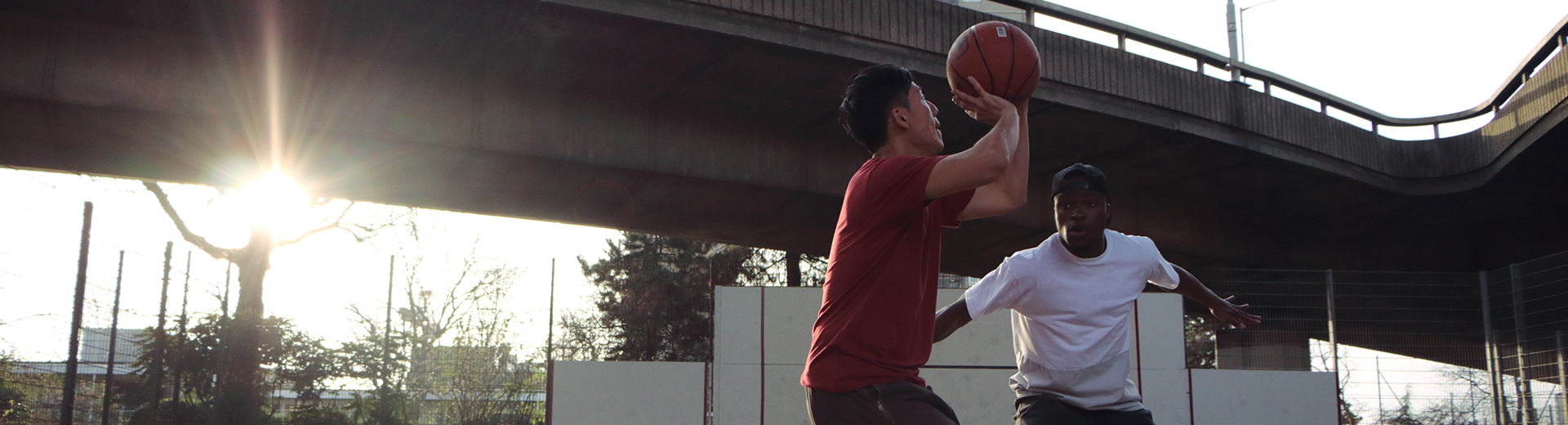 2 men playing basketball with sunlight behind them